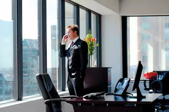 A professional man in a suit answering a phone call in his private office space